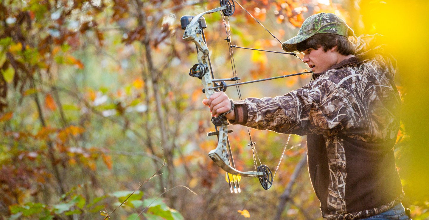 southern american teen boy out in the woods bow hunting for deer